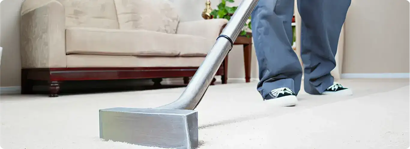 Carpet cleaning technician using a hot-water extraction wand on a light-colored carpet in a living room, Huntsville, AL.