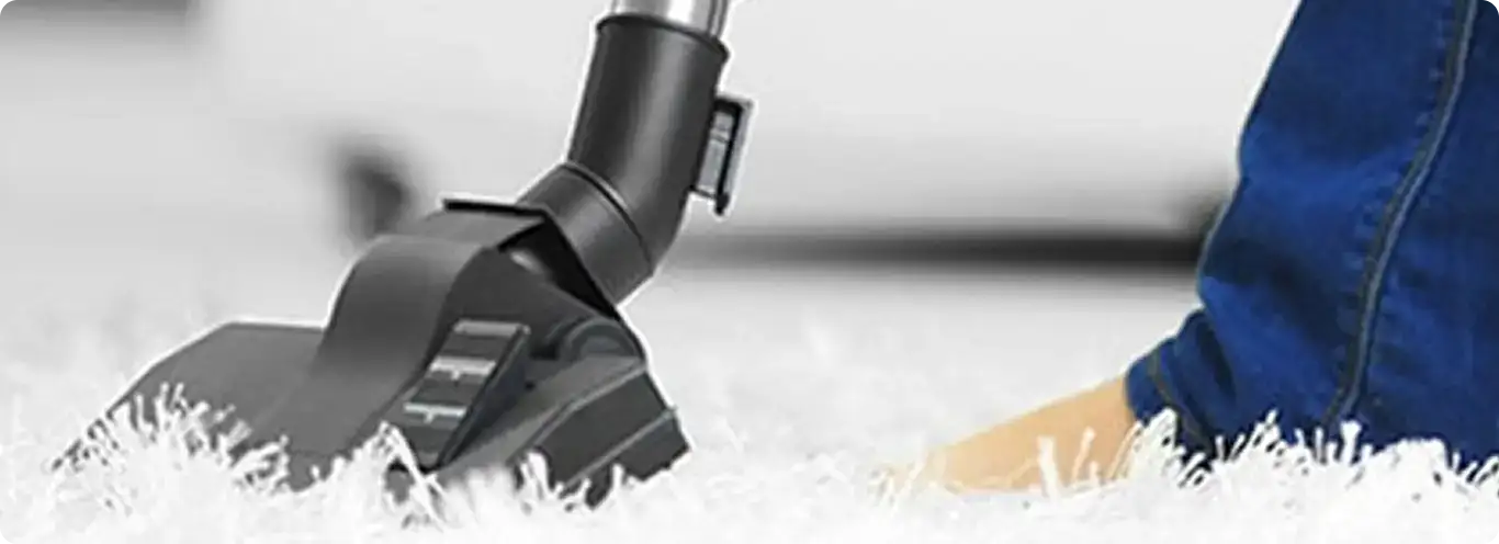 Close-up of a professional vacuuming a white carpet in Valhermoso Springs.