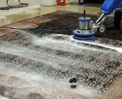 Professional rug cleaning with a rotary floor machine and shampoo foam, deep-cleaning an area rug, in Huntsville, AL.